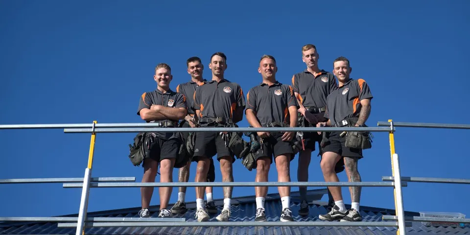 The Primeline Roofing team standing on a Colorbond metal roof in Wollongong, NSW